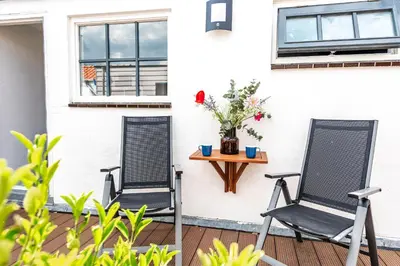two chairs on a porch with a table and flowers at 't Duinpannetje in Zandvoort