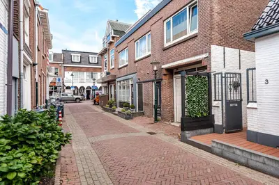 a brick alley way with buildings and a door at 't Duinpannetje in Zandvoort