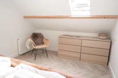 a bedroom with a bed and a chair and a dresser at Kelp in Egmond aan Zee