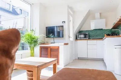 a living room with a table and a kitchen at Kelp in Egmond aan Zee