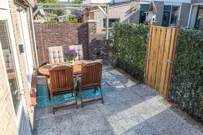 a patio with a wooden table and chairs and a fence at Kelp in Egmond aan Zee