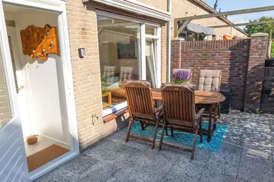 a patio with a wooden table and chairs on a porch at Kelp in Egmond aan Zee