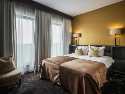a hotel room with a large bed and a chair at Van der Valk Hotel Hoorn in Hoorn