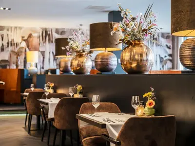 a restaurant with tables and vases with flowers on the wall at Van der Valk Hotel Hoorn in Hoorn
