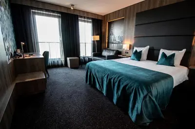 a hotel room with a large bed and a chair at Van der Valk Hotel Hoorn in Hoorn