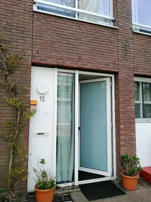 a large door on a brick building with two plants at All you need, a comfy place in Amsterdam