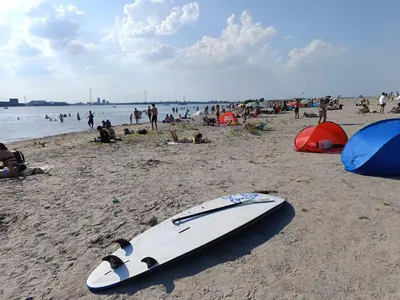 a surfboard laying on a beach with a crowd of people at All you need, a comfy place in Amsterdam