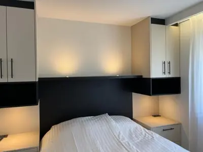 a bedroom with a white bed and white cabinets at Casa del Cisne 3 in Zandvoort