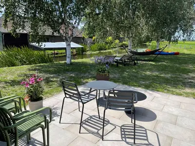 a patio with a table and chairs and a hammock at B&B De Meije in Nieuwkoop