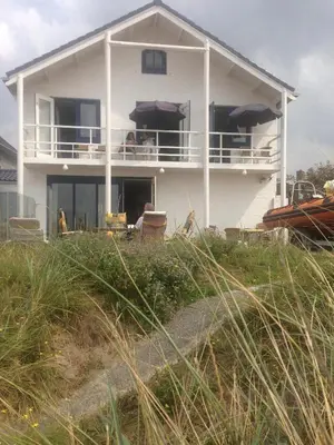 a white house with people sitting on the balcony at Zee en Duin in Zandvoort