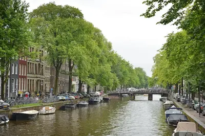 a river with cars parked on the side and a bridge at Luxueuze Studio Herengracht in Amsterdam
