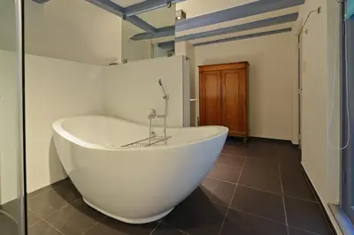 a white bath tub in a bathroom with a tile floor at Luxueuze Studio Herengracht in Amsterdam
