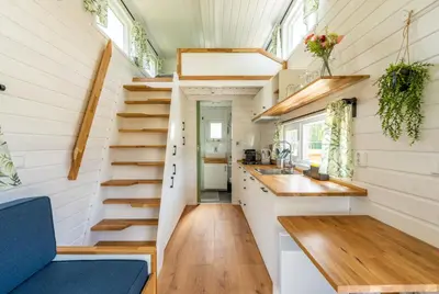 a tiny house with stairs and a kitchen at Green Tiny House with shared pool in Zeewolde