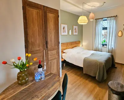 a bedroom with a bed and a table with flowers at Have a nice stay! - Studio tussen de bossen en de bollenvelden in Noordwijkerhout