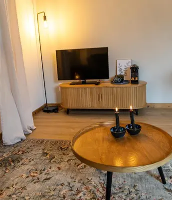 a living room with a coffee table and a flat screen tv at Have a nice stay! - Studio tussen de bossen en de bollenvelden in Noordwijkerhout