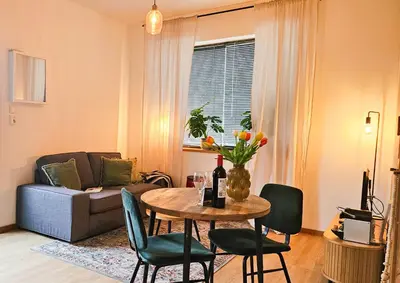 a living room with a table and chairs and a couch at Have a nice stay! - Studio tussen de bossen en de bollenvelden in Noordwijkerhout