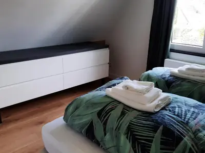 a bedroom with two beds and a white dresser at Stylish holiday home by the sea in Tuitjenhorn