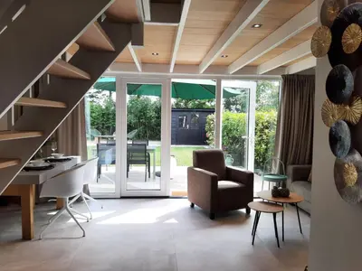 a living room with a staircase and a chair at Stylish holiday home by the sea in Tuitjenhorn