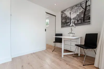 a white room with a desk and two chairs at Happy Days Apartment - Luxurious - Free parking on own property in Zandvoort