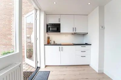 a kitchen with white cabinets and a window at Happy Days Apartment - Luxurious - Free parking on own property in Zandvoort