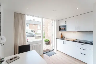 a kitchen with white cabinets and a large window at Happy Days Apartment - Luxurious - Free parking on own property in Zandvoort