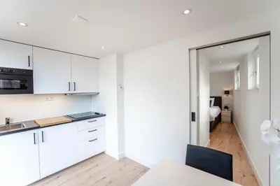 a kitchen with white cabinets and a table with a chair at Happy Days Apartment - Luxurious - Free parking on own property in Zandvoort