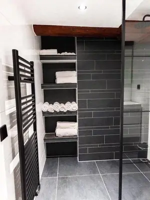 a walkin closet with black tile and white towels at Appartement Wolf in Alkmaar