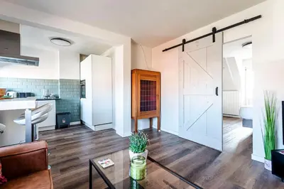 a living room with a sliding door and a table at Albatros aan Zee - Apartment in Zandvoort