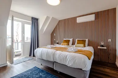 a bedroom with a large bed and a large window at Albatros aan Zee - Apartment in Zandvoort