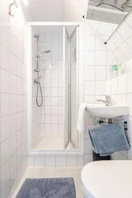 a white bathroom with a shower and a sink at Albatros aan Zee - Apartment in Zandvoort