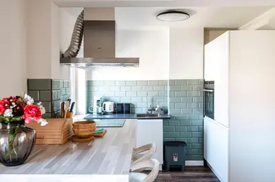 a kitchen with white cabinets and a vase of flowers at Albatros aan Zee - Apartment in Zandvoort