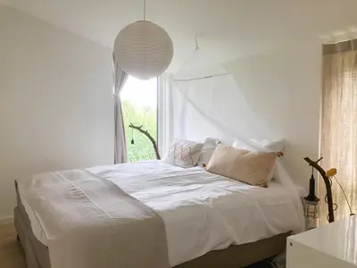 a bedroom with a white bed with a window at Bungalow 82 op Recreatiepark De Wielen in Sint Maarten