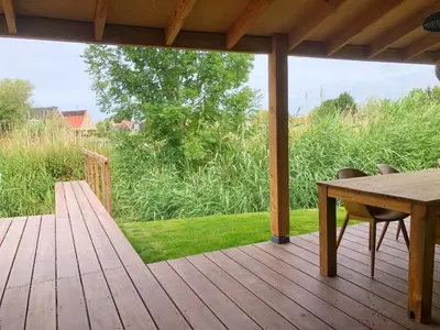a wooden deck with a table and chairs on it at Bungalow 82 op Recreatiepark De Wielen in Sint Maarten