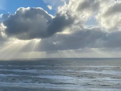 a cloudy sky over the ocean with people in the water at Zwarte Vis in Zandvoort
