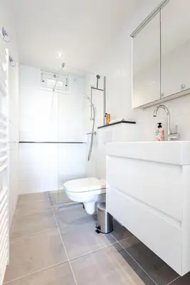 a white bathroom with a toilet and a sink at The apartment Shell 42 in Zandvoort