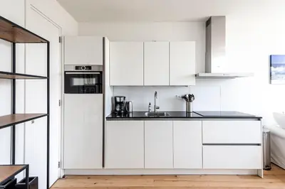 a white kitchen with white cabinets and a sink at The apartment Shell 42 in Zandvoort