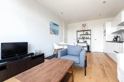 a living room with a tv and a blue chair at The apartment Shell 42 in Zandvoort