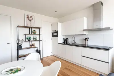 a kitchen with white cabinets and a white table and chairs at The apartment Shell 42 in Zandvoort