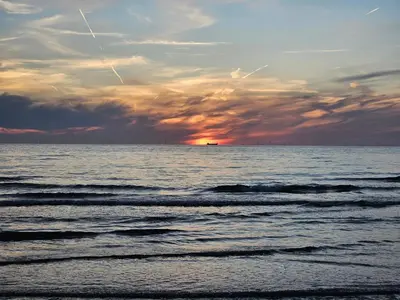 a sunset over the ocean with a ship in the distance at Super de luxe privékamer op een toplocatie - Room 1 in Egmond aan Zee
