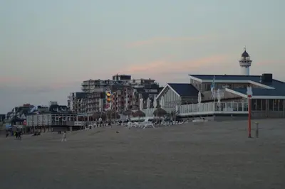a beach with a group of buildings and a lighthouse at Super de luxe privékamer op een toplocatie - Room 1 in Egmond aan Zee