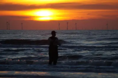 a person standing in the ocean watching the sunset at Super de luxe privékamer op een toplocatie - Room 1 in Egmond aan Zee