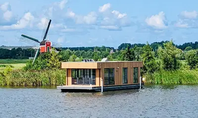 a small house on the water with a windmill at Surla houseboat 