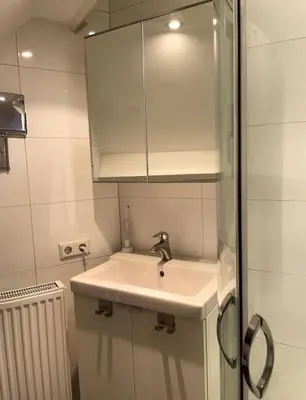 a white bathroom with a sink and a mirror at AA Centrum Appartement in Zandvoort