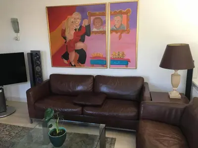 a living room with a brown leather couch and a painting at AA Centrum Appartement in Zandvoort