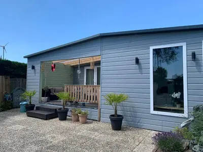 a gray house with potted plants in front of it at Oase aan de Kaag in Warmond