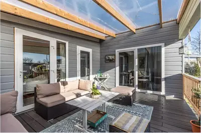 a patio with a couch and a table on a deck at Oase aan de Kaag in Warmond