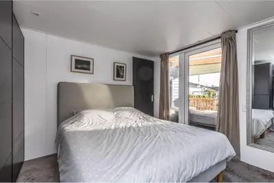 a white bedroom with a bed and a window at Oase aan de Kaag in Warmond