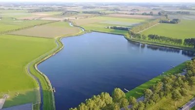 an aerial view of a river with green fields at Bij het meertje! in Dirkshorn