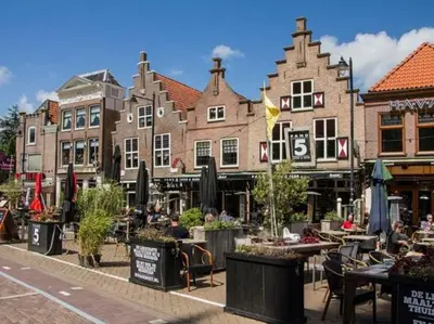a group of buildings on a street with tables at Bij het meertje! in Dirkshorn