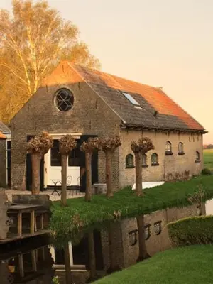 a large brick building with an orange roof at B&B De Beijersche Stee, Logies aan de Waterkant in Stolwijk